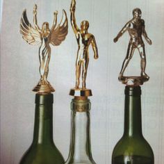 three wine bottles with statues on top of them