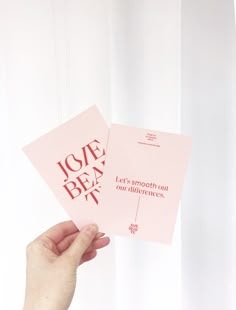 someone holding up two pink cards with the words love is in red and white on them