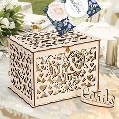 a wooden box with cut out hearts and initials on the lid sitting on a table