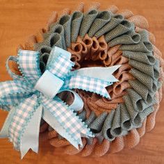 a close up of a wreath on a wooden table with blue and white ribbon tied around it