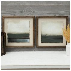 two framed paintings sitting on top of a shelf