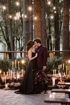 a bride and groom standing in front of candles at their outdoor wedding ceremony with lights strung from the trees