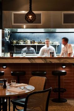 two men are behind the counter in a restaurant