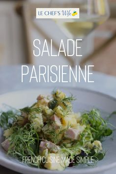 a white plate topped with salad next to a glass of wine