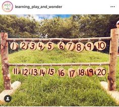 a wooden sign with numbers hanging from it's sides in front of some grass