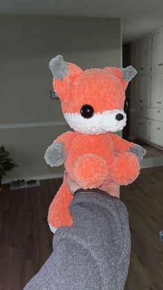 a person holding a small stuffed animal in their hand