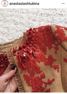 a woman is stitching red lace on a piece of burlocked fabric