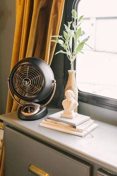 an air conditioner sitting on top of a table next to a vase with a plant