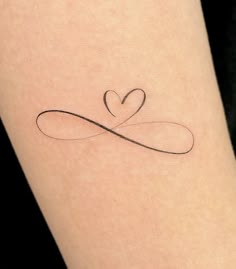 a heart shaped tattoo on the leg of a woman's arm with an infinite love symbol