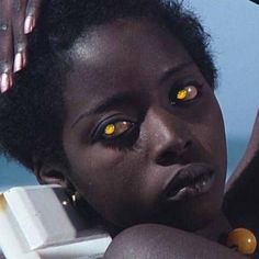 a woman with yellow eyes holding a cell phone