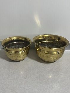 two brass bowls sitting on top of each other, one is empty and the other has no