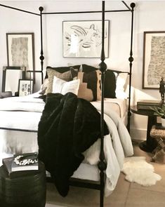 a bedroom with a four poster bed and white walls, black accents on the headboard