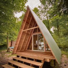 a - frame cabin in the woods with stairs leading up to it