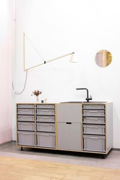 a large gray cabinet with drawers and a sink in the middle is next to a white wall