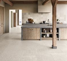 a kitchen with an island counter top and wooden beams on the ceiling, along with white tile flooring