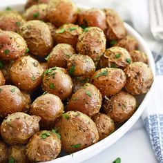 a white bowl filled with cooked potatoes and parsley