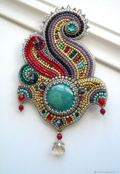 a brooch with beads and stones on the back of it's neck, hanging from a window sill