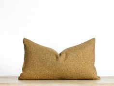 a brown pillow sitting on top of a wooden table next to a white wall,