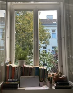 an open window with books and plants in front of it