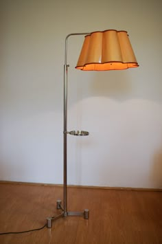 a lamp that is on top of a wooden floor in front of a white wall