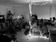 a group of people sitting on couches in a living room with string lights strung across the ceiling