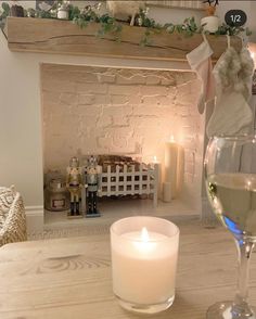 a glass of wine sitting on top of a wooden table next to a lit candle