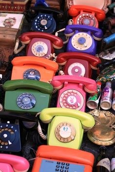 many different colored telephones sitting on top of each other