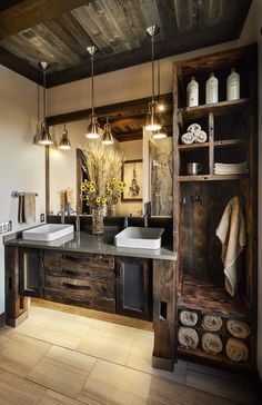 a bathroom with double sinks and wooden cabinets in it's center area, along with two hanging lights