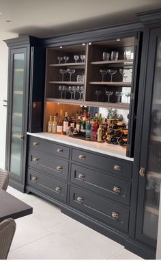 an empty bar with wine glasses on the top and bottles in the bottom cabinet,