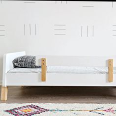 a white day bed sitting on top of a hard wood floor next to a rug