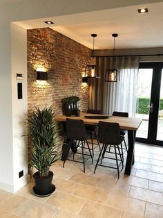 a dining room table with chairs and a potted plant in front of the door