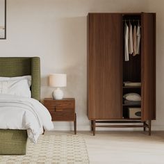 a bedroom with a green armoire next to a white bed and beige carpeted floor