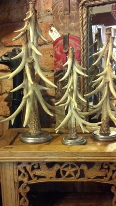 some very pretty white christmas trees in front of a mirror on a wooden table with rope