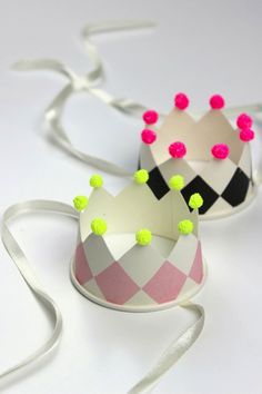 two paper crowns with pom - poms on them sitting next to each other