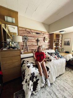 a woman sitting on top of a bed in a bedroom next to a wooden headboard