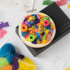 there is a bowl of colorful beads on the table next to some scissors and other crafting supplies