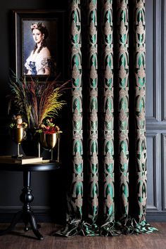 the curtains in this room are decorated with green and brown patterns, along with a small side table