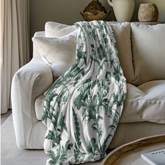 a living room with a white couch covered in a green and white floral print blanket