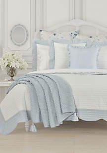 a bed with white and blue comforters in a room