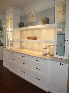 a kitchen with white cabinets and marble counter tops