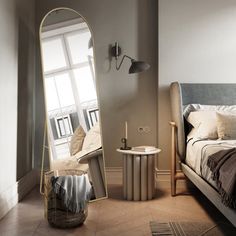 a bed sitting next to a large mirror in a bedroom on top of a hard wood floor