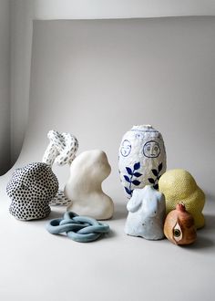 four ceramic sculptures sitting on top of a white surface