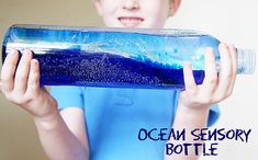 a young boy holding a bottle with blue liquid in it