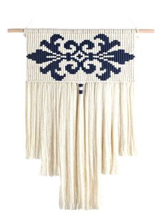 a white and blue wall hanging with fringes