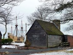 an old wooden house with two boats in the water behind it and snow on the ground