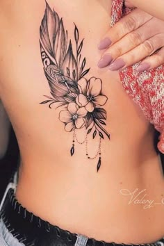 a woman's stomach with a feather and flower tattoo