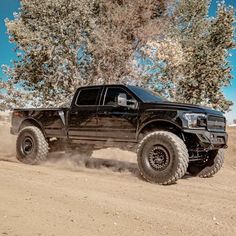 a black truck driving down a dirt road