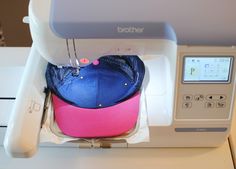 a hat is sitting on top of a sewing machine with a pink and blue cap