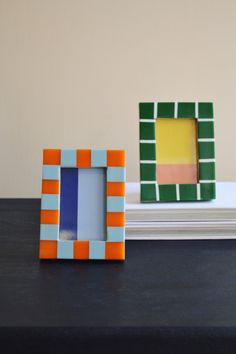 two small colorful frames sitting on top of a table next to each other, one with a square in the middle