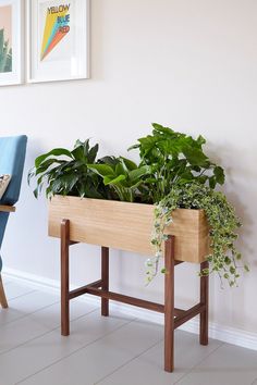 a wooden planter filled with green plants next to a blue chair